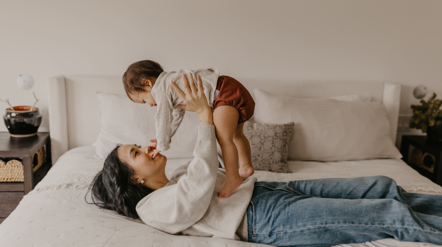 Mother playing with baby on a bed