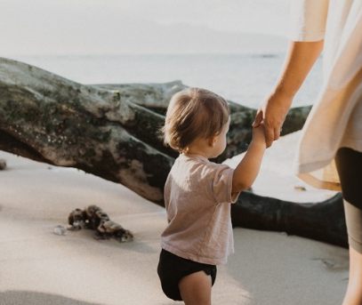 Parent holding toddler on beach