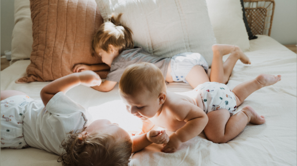 Mother playing with baby on a bed